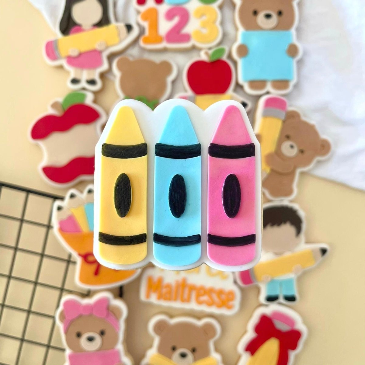 Koekje met drie stiften in geel, blauw en roze tussen andere schoolkoekjes