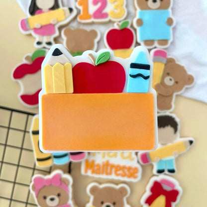 Oranje naambordje koekje met rode appel en potloden tussen schoolkoekjes