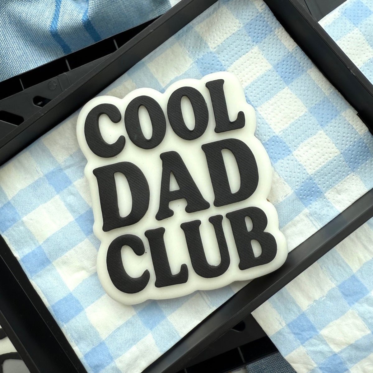 Zwart koekje met Cool Dad Club in witte letters in een zwart doosje