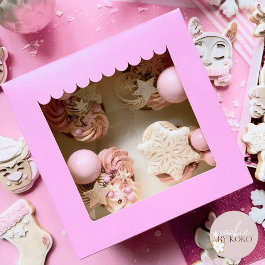 Roze doos voor 4 met kersttraktaties en het logo van een bakker