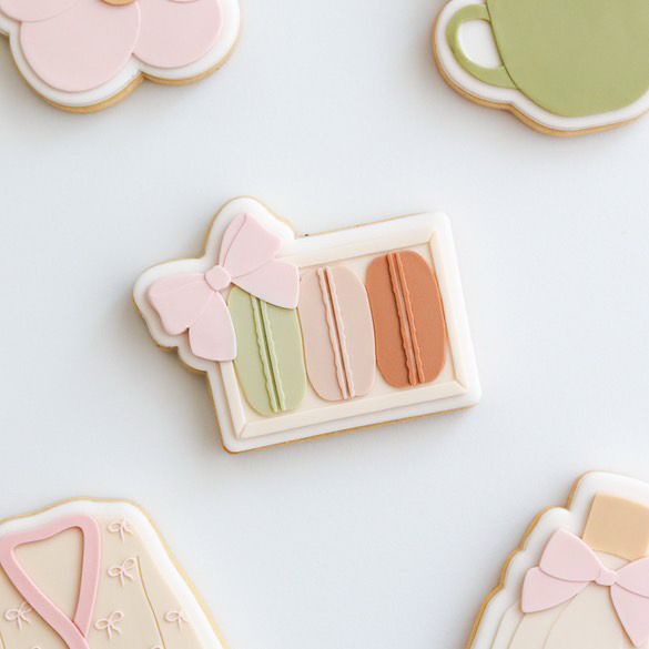 Koekje in de vorm van een macarondoosje met roze strik