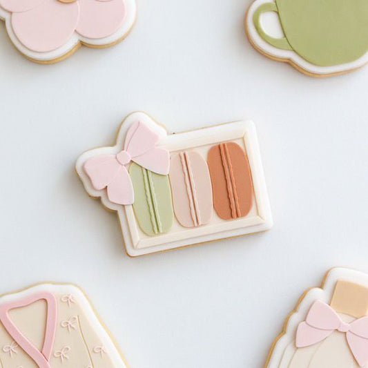 Koekje in de vorm van een macarondoosje met roze strik