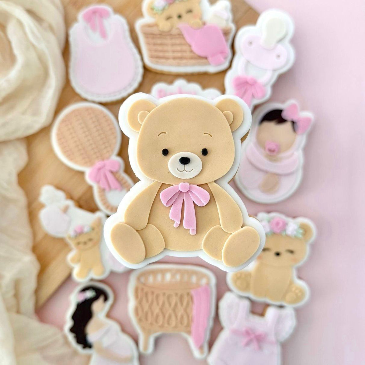 Beige beertje koekje met roze strik tussen babykoekjes